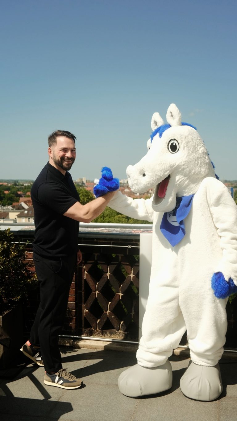 Handshake von Dr. Jeremias Othmann mit dem Maskottchen der Öffentlichen Versicherung Braunschweig Öfi